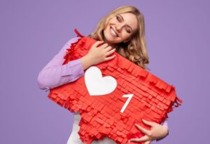 Giovane donna sorridente che tiene un cuore con l'icona "Mi piace", simbolo di engagement sui social media.